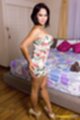 Standing beside bed wearing dress hands on her ass in high heels