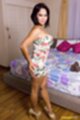 Napassrin standing beside bed wearing summer dress hands on her ass in high heels