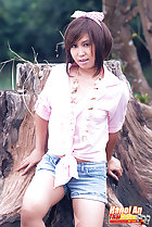 Leaning against tree stump wearing knotted shirt in shorts